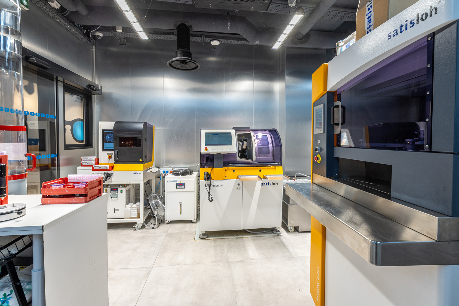 Photo horizontale grand format, intérieur industriel, ambiance technologique, lumière artificielle, environnement propre et professionnel, machines visibles, couleurs dominantes gris métal, blanc et jaune, absence de personnes, contexte de recherche et fabrication avancée.